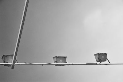 Bird perching on cable against sky