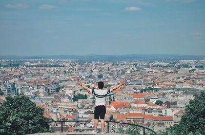 Rear view of man standing by cityscape against sky