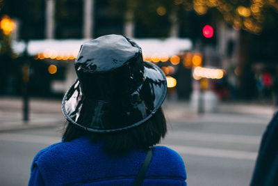 Rear view of woman with umbrella on street in city