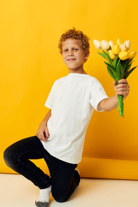 Full length of young woman standing against yellow background