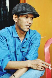 Portrait of man wearing hat sitting outdoors