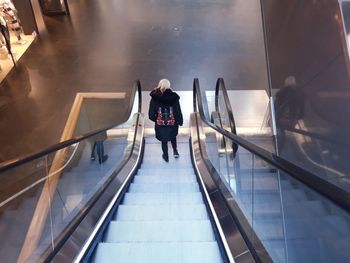 Rear view of woman standing on escalator