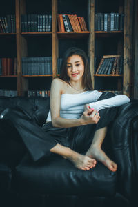 Young woman using digital tablet while sitting on sofa at home