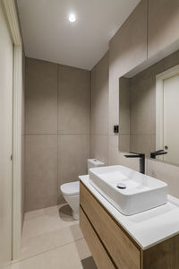 Interior of modern style bathroom in refurbished apartment. narrow toilet with sink and black faucet 
