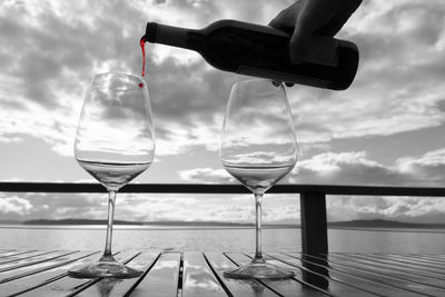 Pouring red wine on outdoor deck table, monochrome, selective color red.