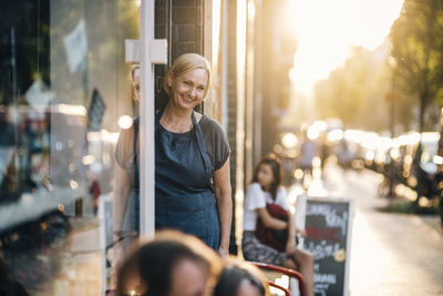 Portrait of woman smiling while standing in store during sunset