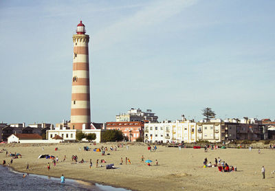 People by lighthouse against sky