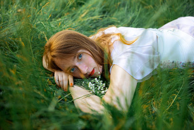 Redhead woman relaxing on the green grass.