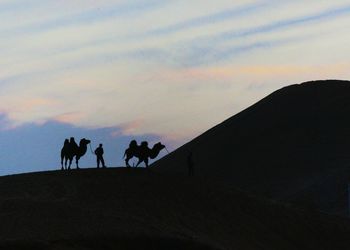 Silhouette men against sky during sunset