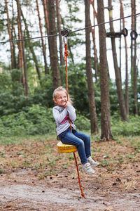 Full length of boy on swing in forest