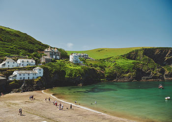 People on beach by buildings against clear sky at port isaac in cornwall, england