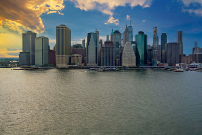 Modern buildings by river against sky in city