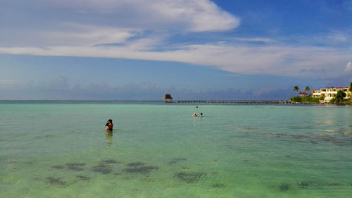 People on beach against cloudy sky