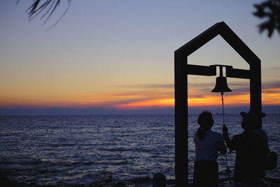 Silhouette people at beach against sky during sunset