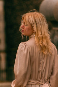 Portrait of young woman looking away while standing outdoors