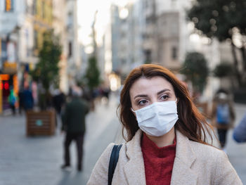 Woman wearing mask looking away standing on city street