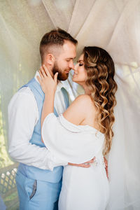 Newlywed couple embracing while standing outdoors