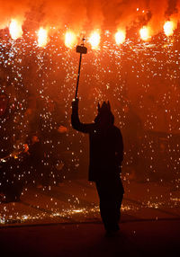 Silhouette man standing against fireworks at night