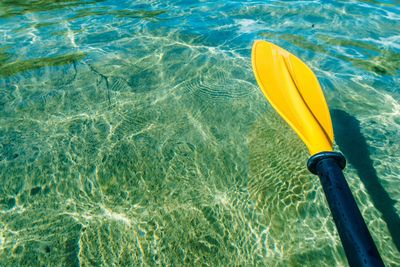 High angle view of yellow oar rowing in sea during sunny day