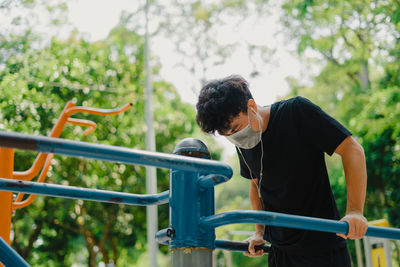 Rear view of man looking at railing against trees