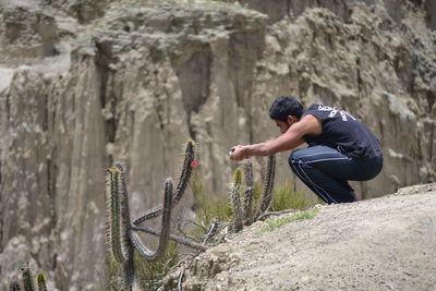 Young man clicking photograph of cactus growing on field