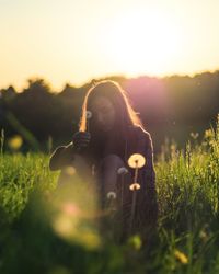 Woman photographing on field during sunset