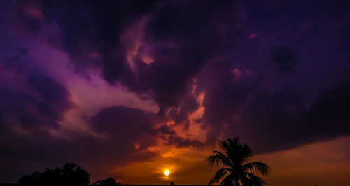 Low angle view of silhouette trees against dramatic sky