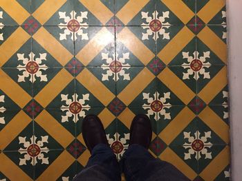 Low section of man standing on multi colored tiled floor