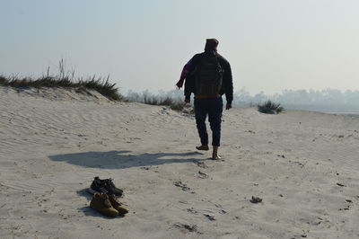 Rear view of man walking on snow land