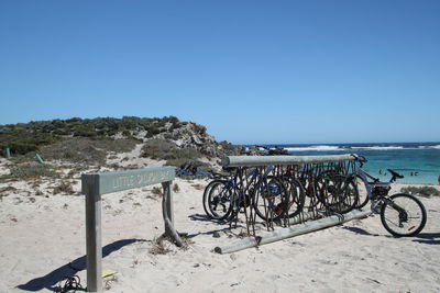 Bicycle on beach against clear blue sky