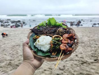 Midsection of person holding sea food on beach