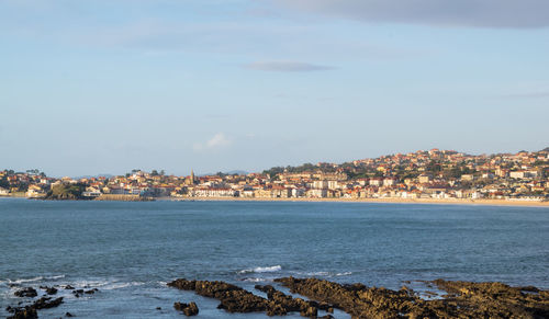 Scenic view of sea by buildings against sky