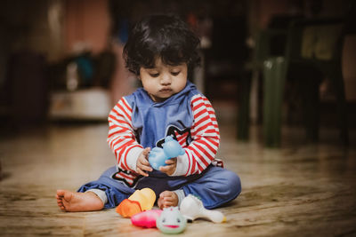 Cute boy with toy sitting on floor