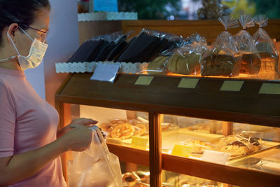A woman choosing the pastry product in a bakery shop during the covid-19 pandemic