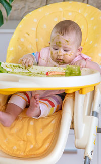 Portrait of cute baby boy sitting on sofa at home