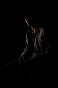 Teenage boy looking away against black background