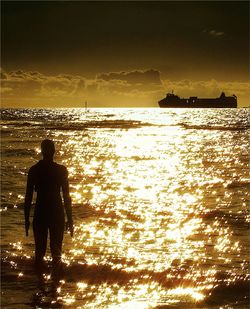 Silhouette of people standing on beach at sunset