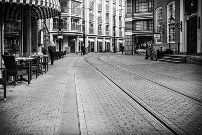 Empty footpath amidst buildings in city