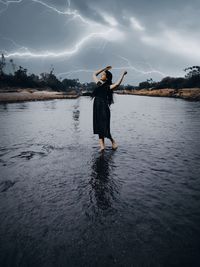 Woman standing in lake against sky