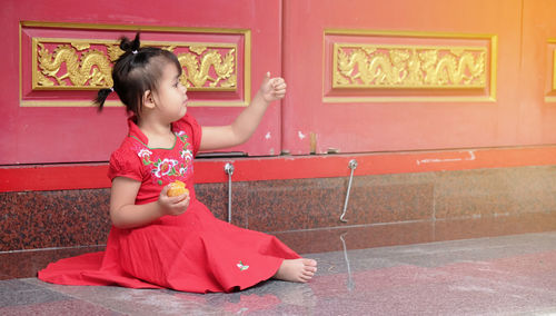 Side view of cute girl sitting against door