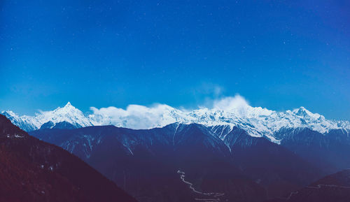 Scenic view of snowcapped mountains against blue sky