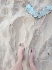 Low section of woman standing at sandy beach