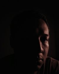 Close-up portrait of young man against black background