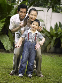 Parents enjoying with son on field at yard