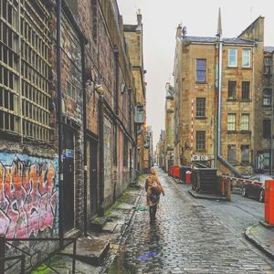 Man walking on street amidst buildings in city