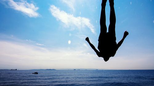 Silhouette of man jumping in sea against sky