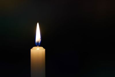 Close-up of lit candle against black background