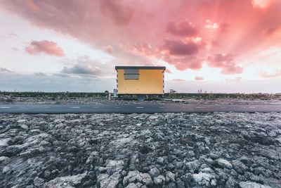 House by road against cloudy sky