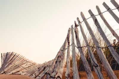 Low angle view of wooden fence at beach against clear sky