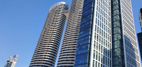 Low angle view of modern buildings against clear blue sky